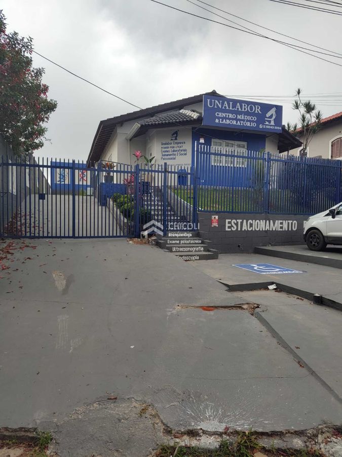 Fachada de clínica médica com sinalização azul e grade de segurança.
