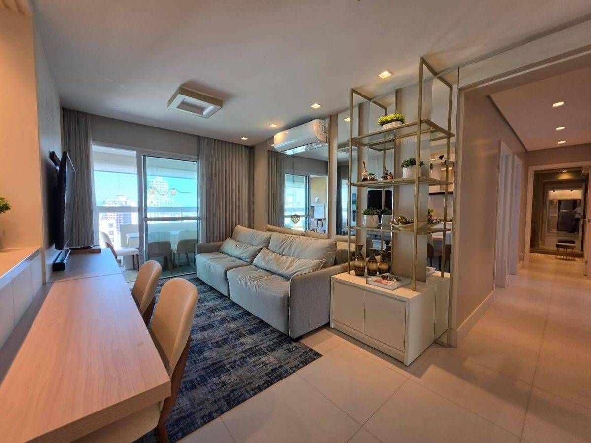 Sala de estar com sofá, televisão, dormitório com cortinas grandes.