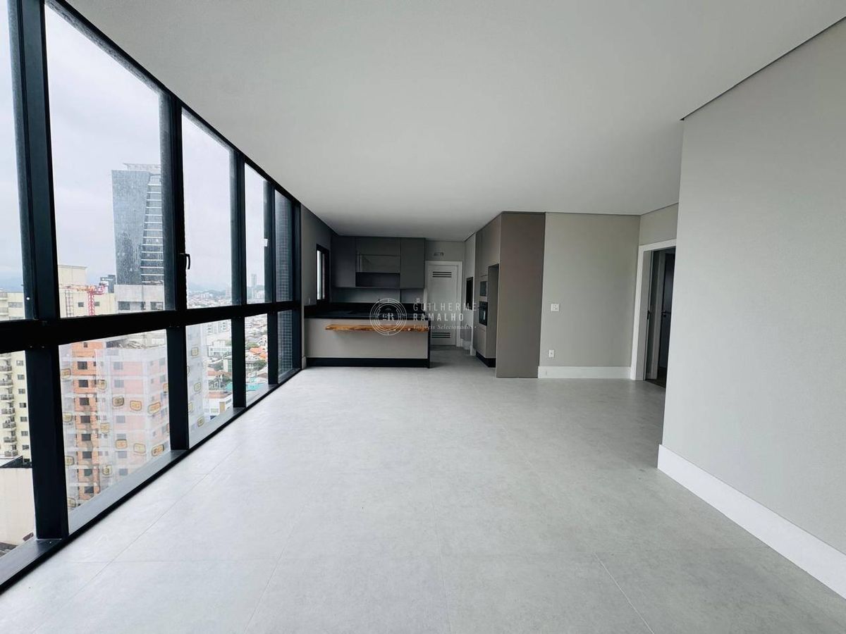 Sala com janelas de vidro, paisagem urbana e acabamento clean.