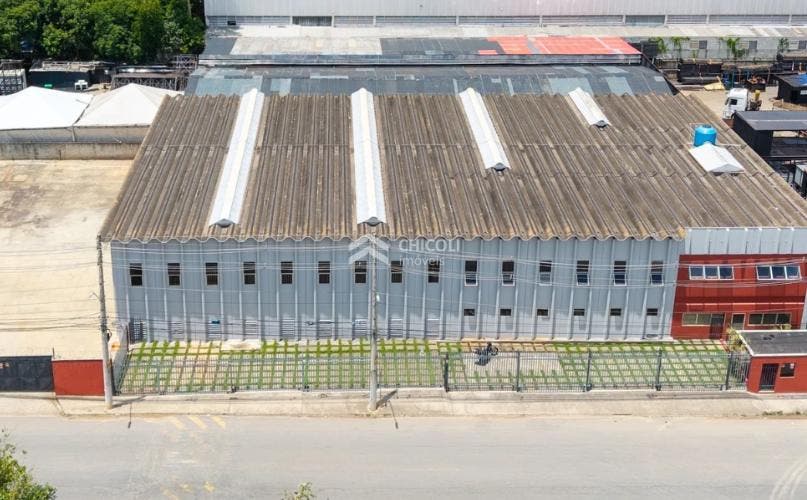 Edifício industrial com cobertura de amianto, muro de grade na frente.