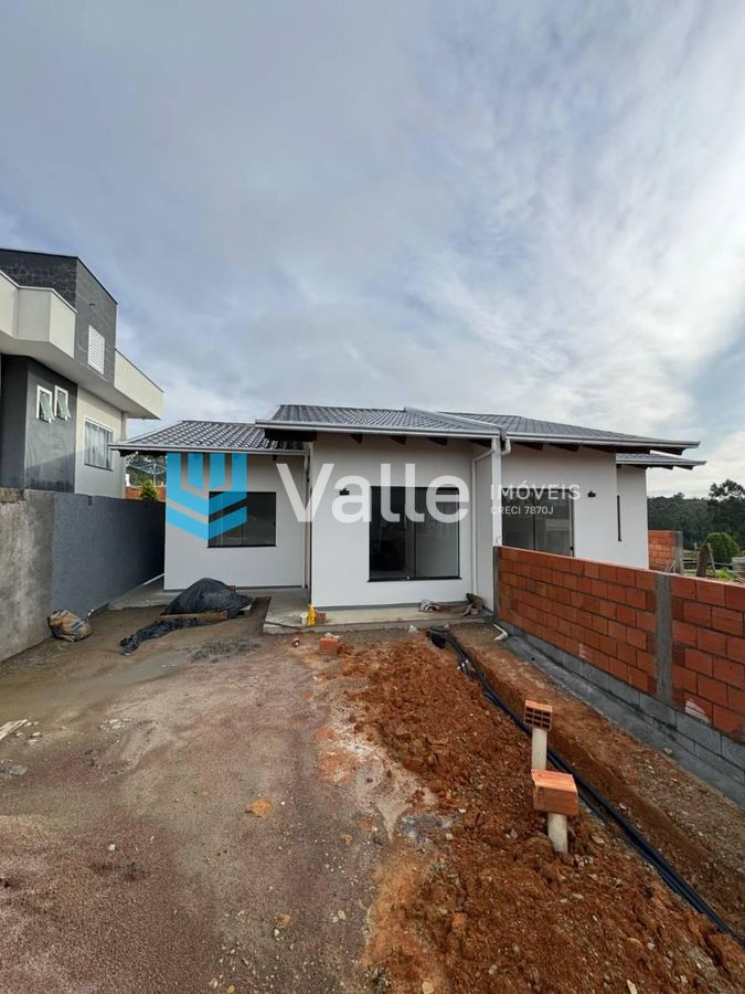 Fachada de casa nova com paredes brancas, janelas grandes e telhado metálico