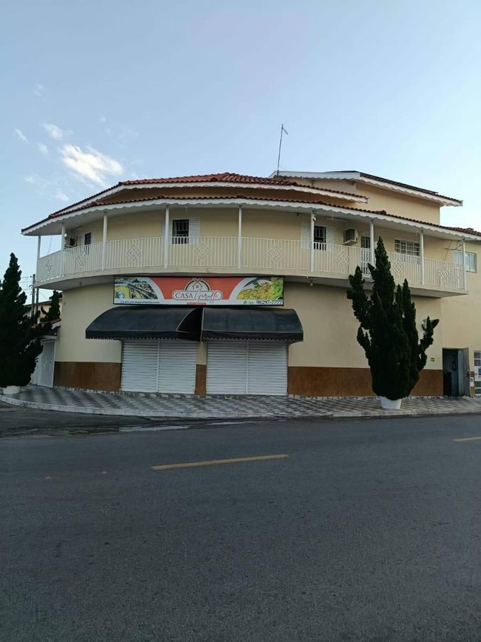 Prédio de dois andares com fachada pintada, guarda-corpos brancos e adesivos.