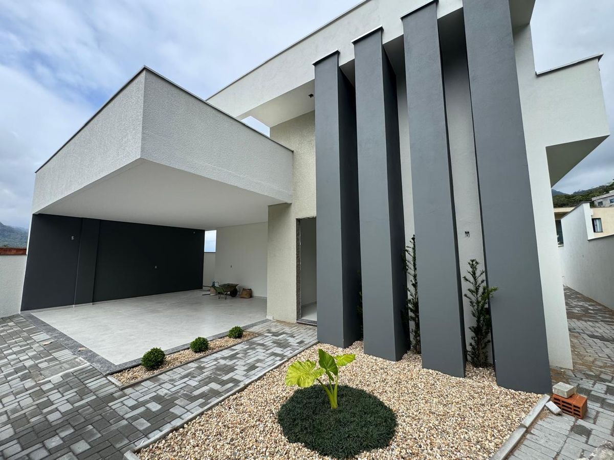 Fachada moderna com elementos cinza, branca e paisagismo minimalista.