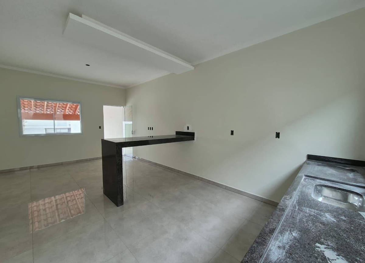 Sala com piso porcelanato e parede branca, cozinha com bancada de granito