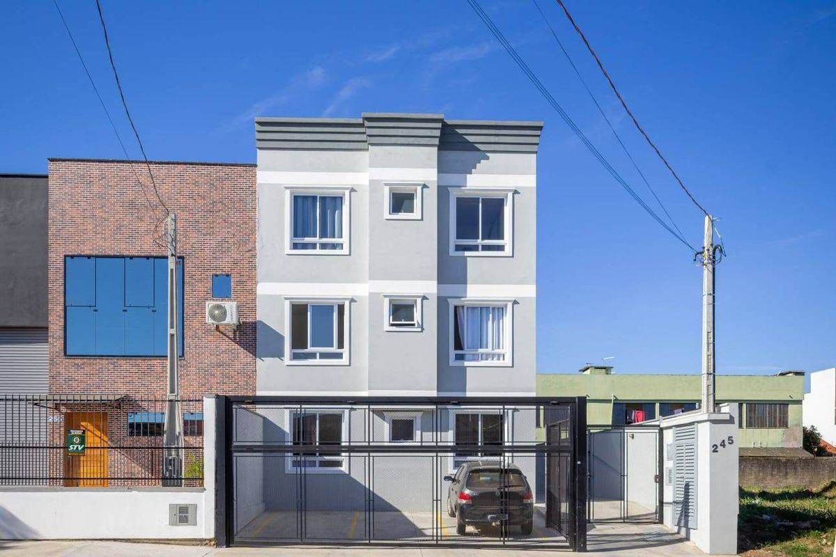 Prédio residencial de três andares com janelas grandes e portão de metal preto