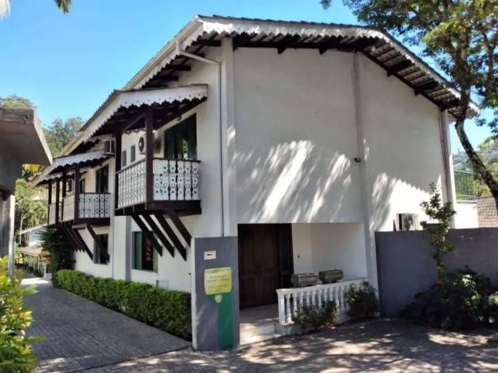 Prédio de alvenaria branco com varandas e telhado de zinco