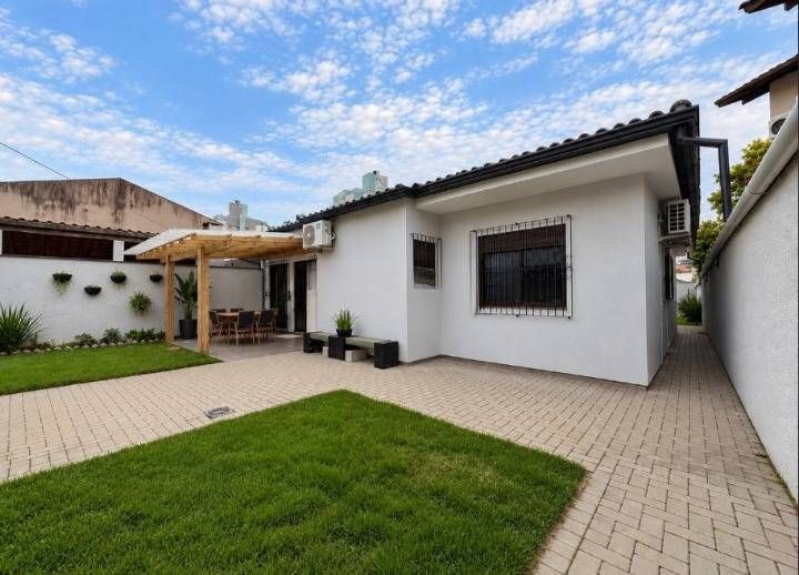 Casa branca com jardim, área de lazer coberta, paredes com plantas.