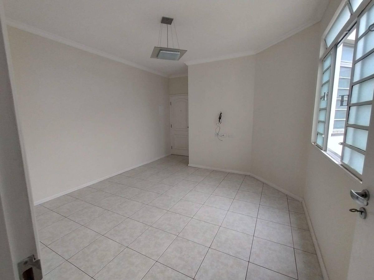 Sala vazia com paredes claras, janela de vidro, piso de cerâmica.