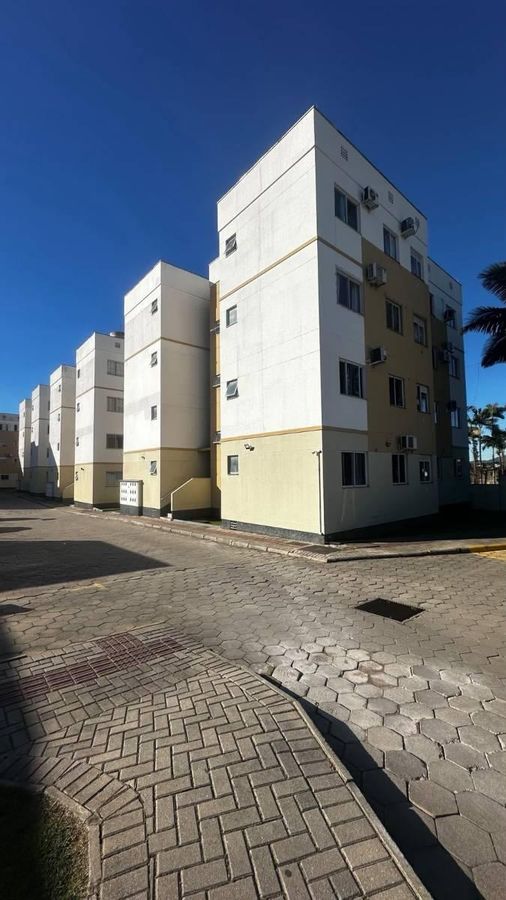 Prédio de apartamentos em área de estacionamento com calçada pavimentada