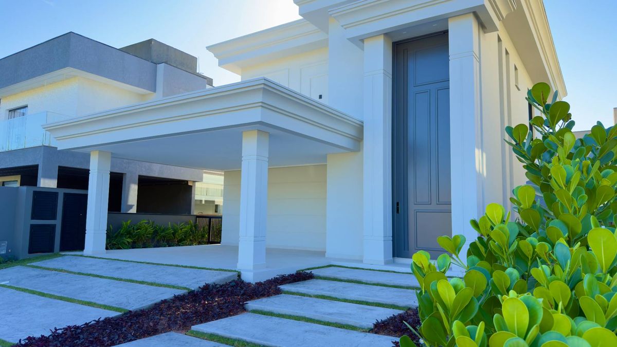 Fachada de residência com detalhes clássicos e acabamento branco