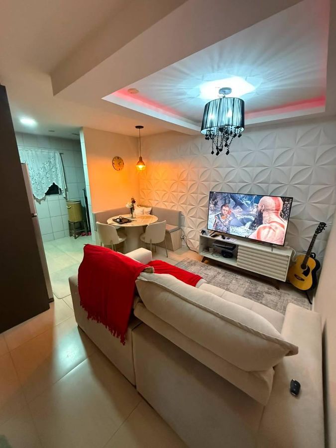 Sala com parede texturizada, teto rebaixado com iluminação e lustre.