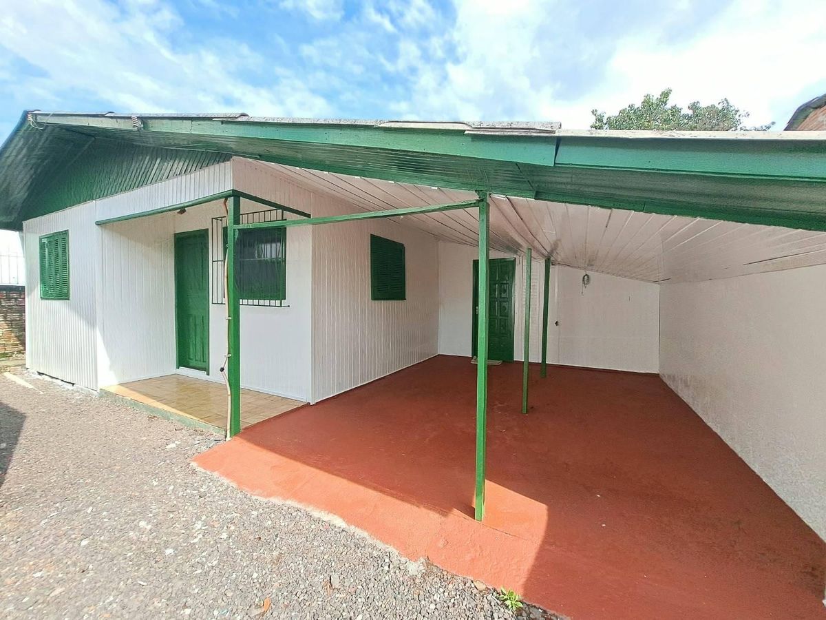 Casa de alvenaria com varanda e toldo verde, área externa simples