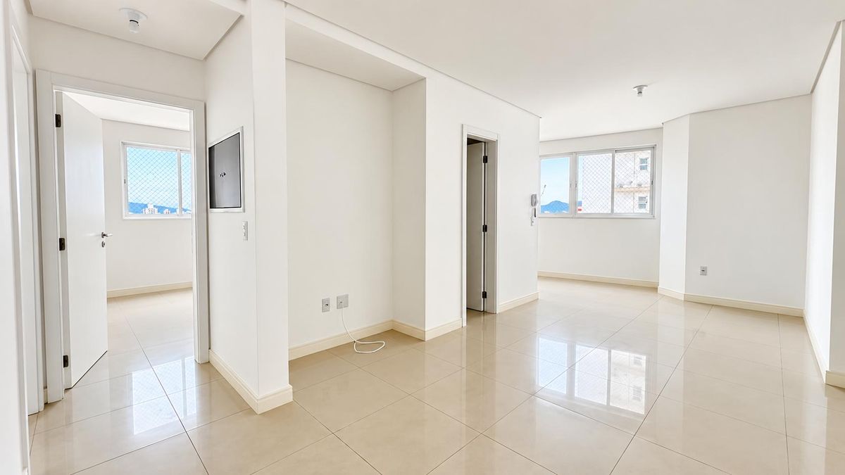 Sala de estar com paredes brancas, janelas grandes e piso de porcelanato.