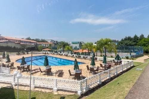 Piscina ao ar livre com espreguiçadeiras e guarda-sóis, cercada por muro branco