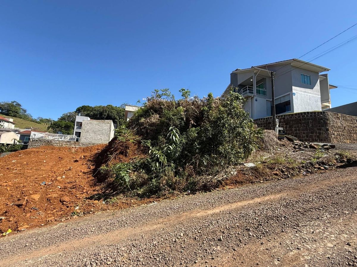 Casa moderna em terreno elevado com muro de pedra e vegetação ao redor