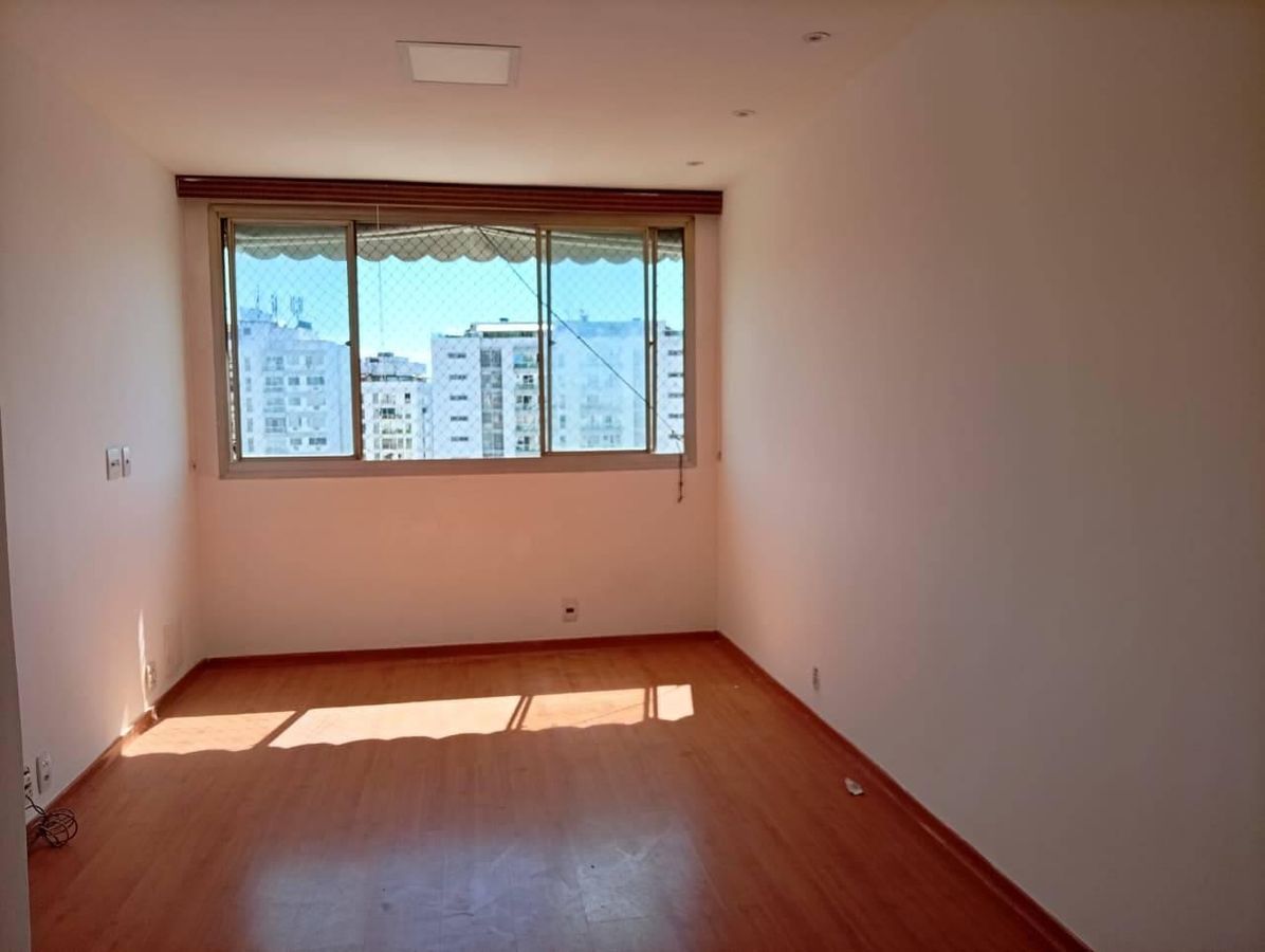 Sala com janela grande e piso de madeira, iluminação natural.