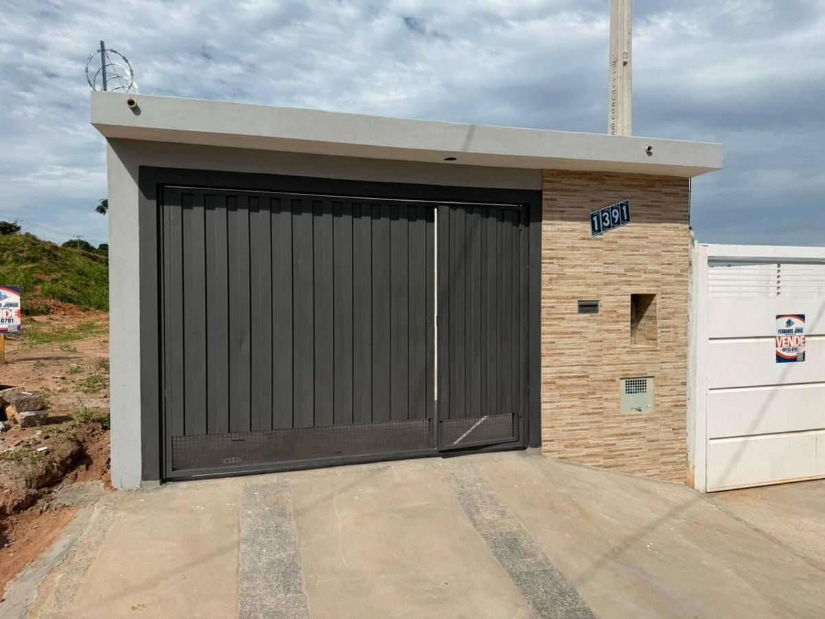 Fachada moderna com portão preto, parede de revestimento em pedra