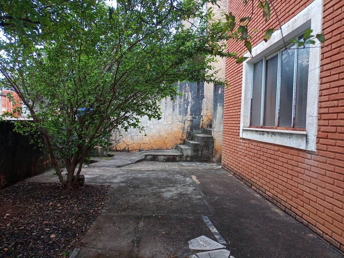Encerramento externo com árvore, parede de tijolos e escadas de concreto
