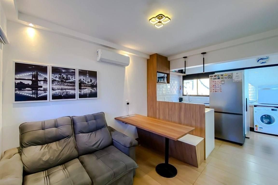Sala integrada à cozinha com acabamento em madeira e paredes brancas