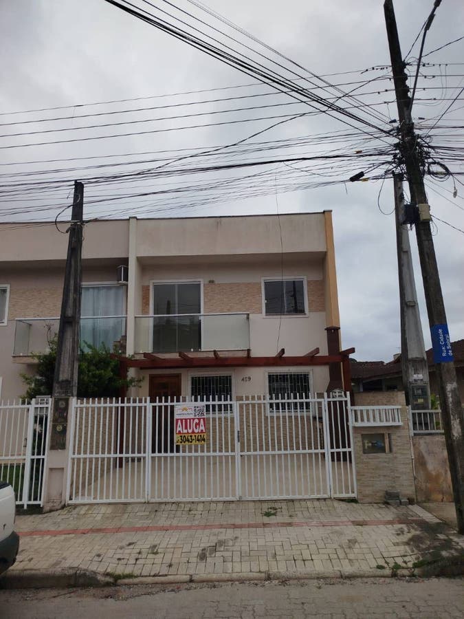 Residência moderna de dois andares com portão branco, telhado em madeira.