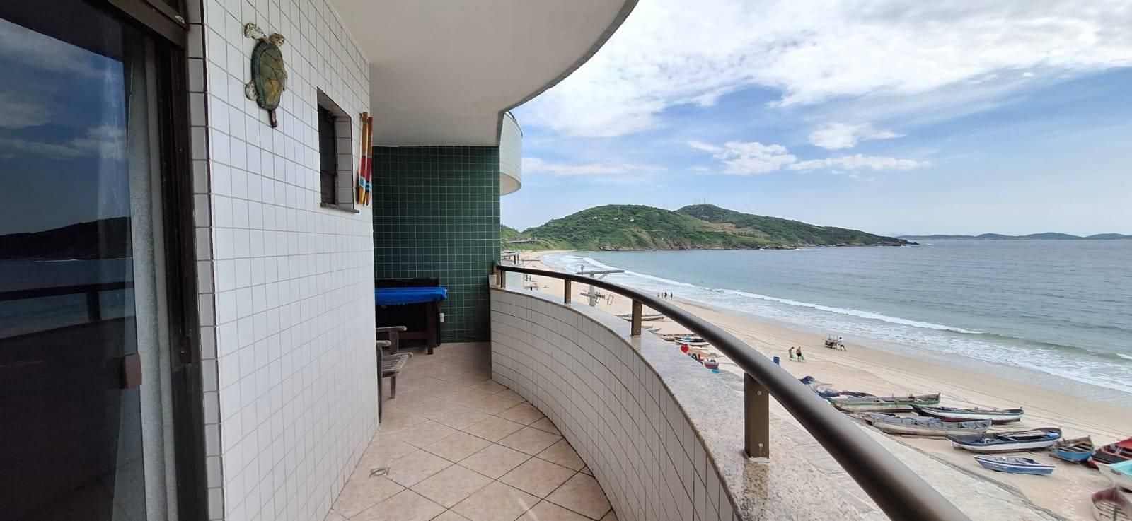 Varanda com parede de azulejos brancos e vista para praia.