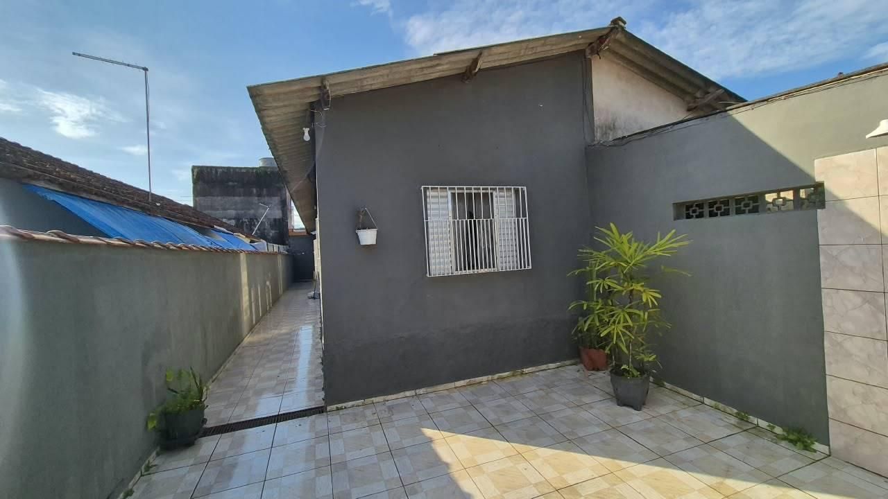 Pátio externo com piso de cerâmica, parede cinza e plantas em vasos