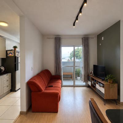 Sala de estar com janela, parede verde, móveis de madeira, iluminação direcionada