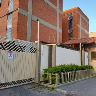 Fachada de prédio com muro de grade, veredas e construção de tijolos.