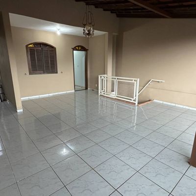 Sala com teto de madeira, paredes bege e piso de azulejo branco