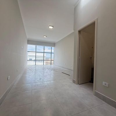 Sala ampla com piso de mármore, paredes brancas, janela de vidro.