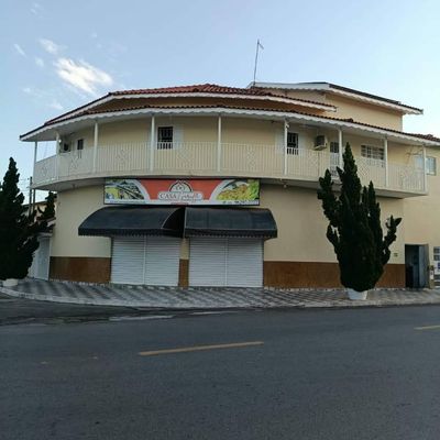 Prédio de dois andares com fachada pintada, guarda-corpos brancos e adesivos.