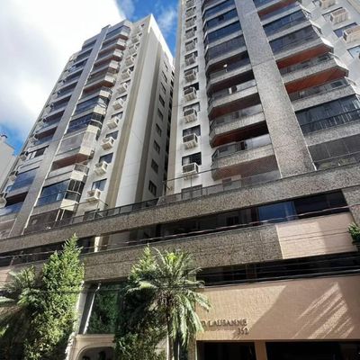 Prédio de várias andares com fachada de vidro e concreto, sob céu azul