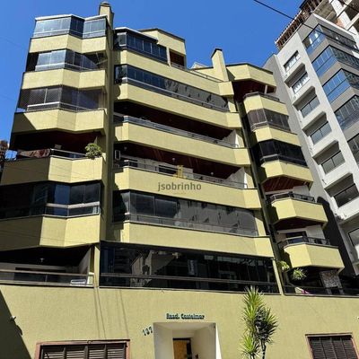 Prédio residencial de vários andares com fachada verde e varandas em vidro
