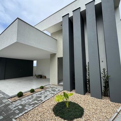 Fachada moderna com elementos cinza, branca e paisagismo minimalista.