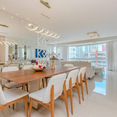 Sala ampla com móveis brancos, iluminação natural e vista urbana