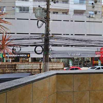 Vista de rua com árvores, postes e fachada de edifício comercial