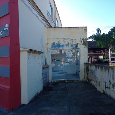 Entrada de comércio com parede avermelhada e vidro na porta