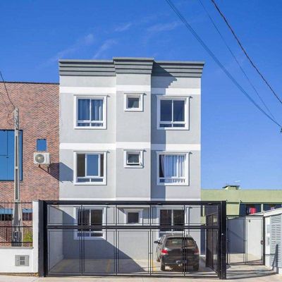 Prédio residencial de três andares com janelas grandes e portão de metal preto