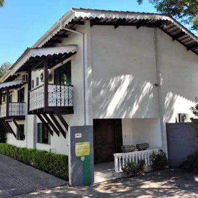 Prédio de alvenaria branco com varandas e telhado de zinco