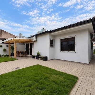 Casa branca com jardim, área de lazer coberta, paredes com plantas.