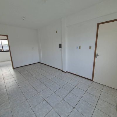 Sala branca com piso de cerâmica, paredes lisas e porta de madeira