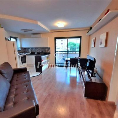 Sala de estar integrada com cozinha, piso de madeira e iluminação central