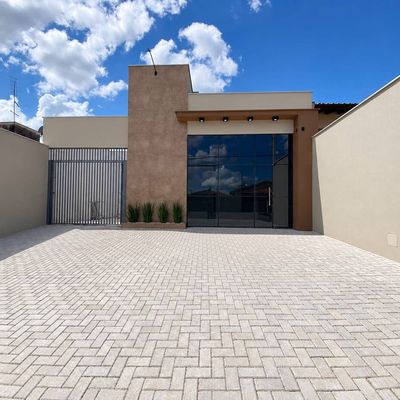 Fachada moderna com vidro, revestimento de textura e jardim pequeno.