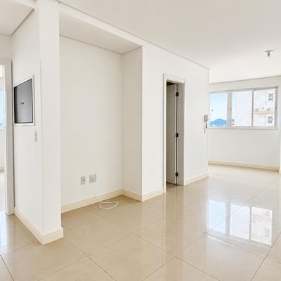 Sala de estar com paredes brancas, janelas grandes e piso de porcelanato.