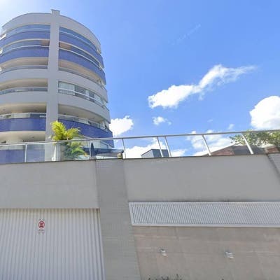 Fachada de edifício residencial com paredes brancas, detalhes em azul e vidro