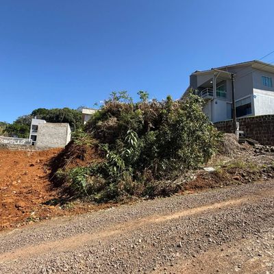 Casa moderna em terreno elevado com muro de pedra e vegetação ao redor