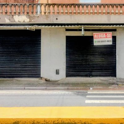Garagem com portas de metal e parede de alvenaria, rua em frente