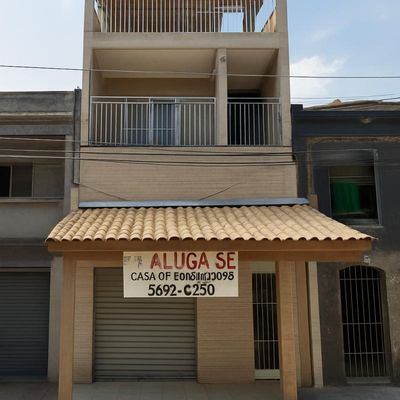 Edifício de três andares com varanda e fachada de alvenaria. (melhorada por IA)