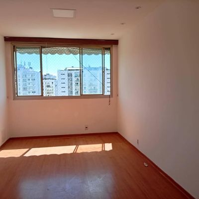 Sala com janela grande e piso de madeira, iluminação natural.