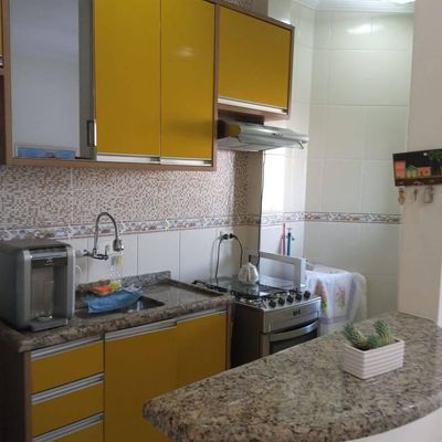 Cozinha com armários amarelos, bancada de granito, paredes revestidas.